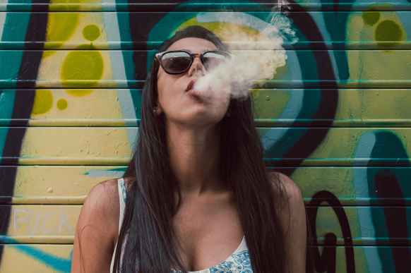 photo of woman wearing sunglasses while smoking